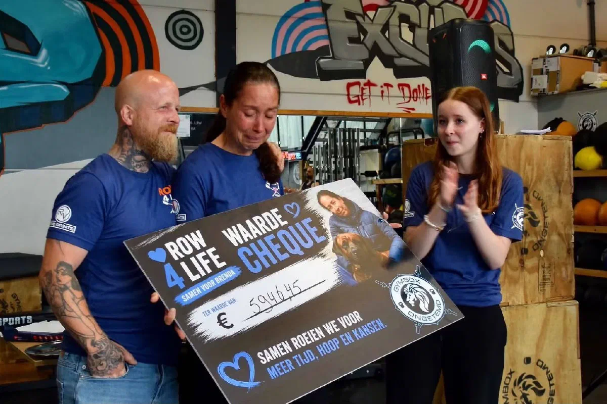 Brenda en haar gezin nemen de Row 4 Life-cheque in ontvangst in de box