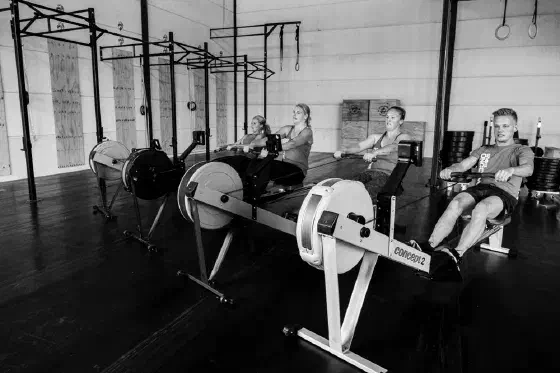 Leden trainen op de roeitrainers tijdens een conditioningles