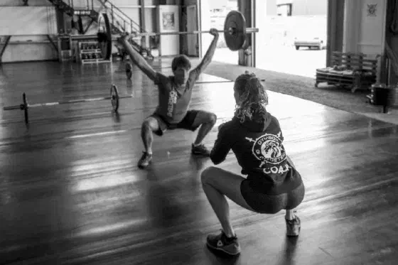 Personal trainer begeleidt een lid bij krachttraining