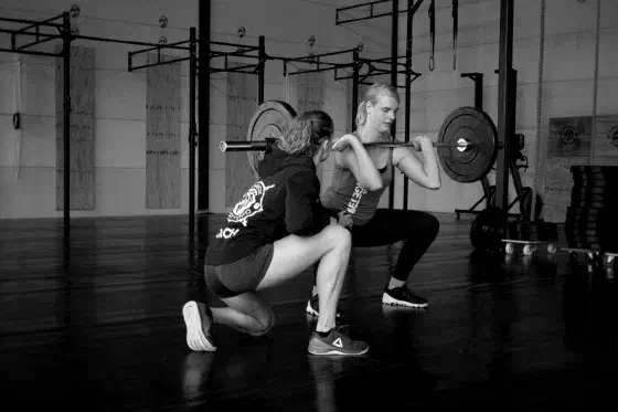 Coach begeleidt een squat tijdens Power Hour